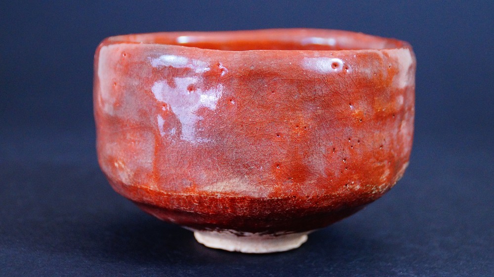 Another side view of the chawan made of Raku ware by Sairi Hotoku with bright red glaze