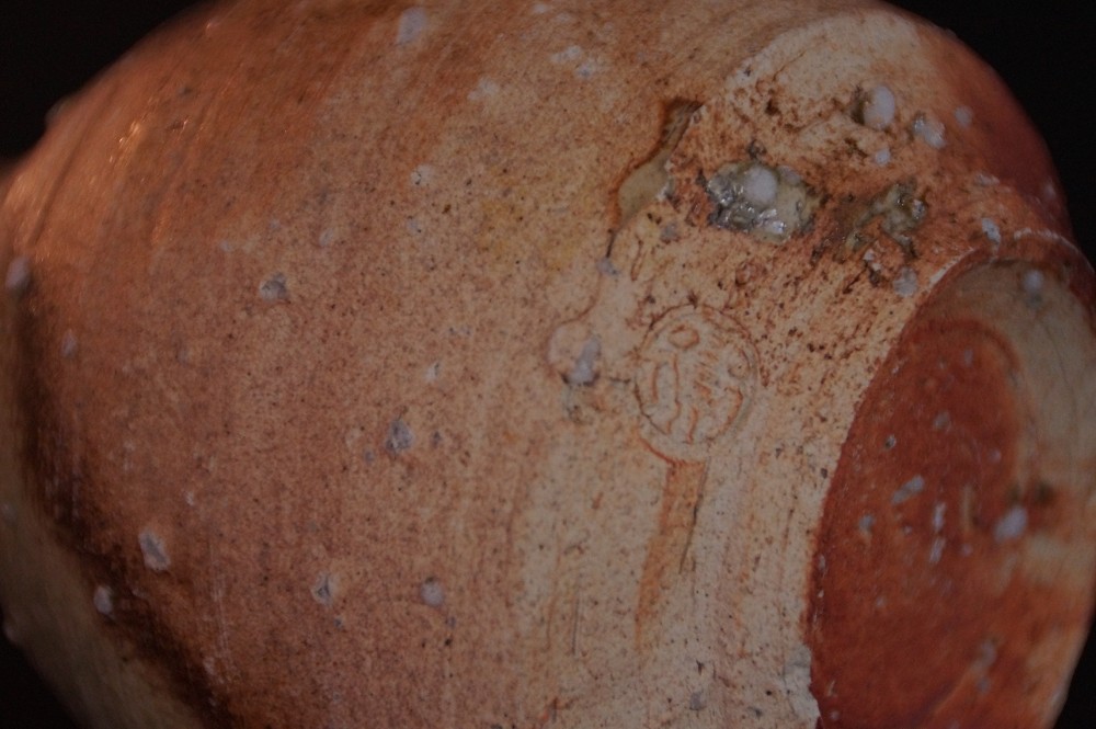 Extreme close-up of the stamped round potter's mark on the foot