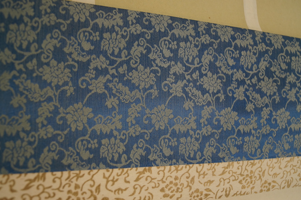 Feigen und Trauben Nahaufnahme der blauen Stoffmontierung mit Bluetenmuster Montierungsdetail