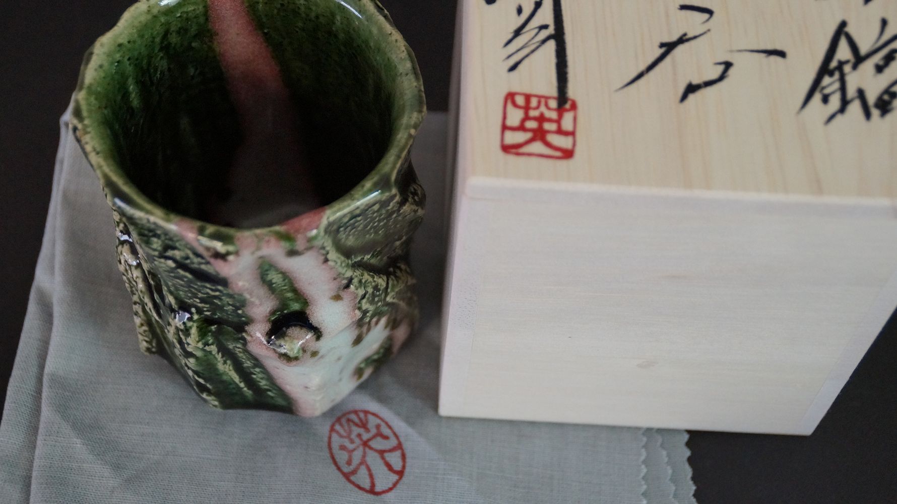 Yunomi tea bowl on gray cloth next to the signed box lid with red artist's seal