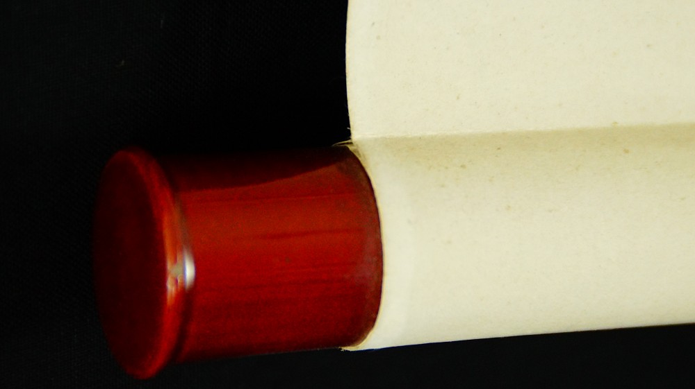 Close-up of the red lacquered roller end of the hanging scroll