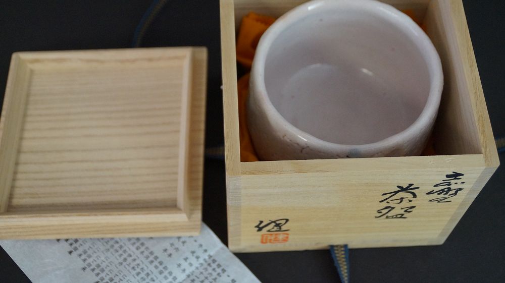 Chawan made of Shino ware in the opened storage box next to the box lid with the artist's signature