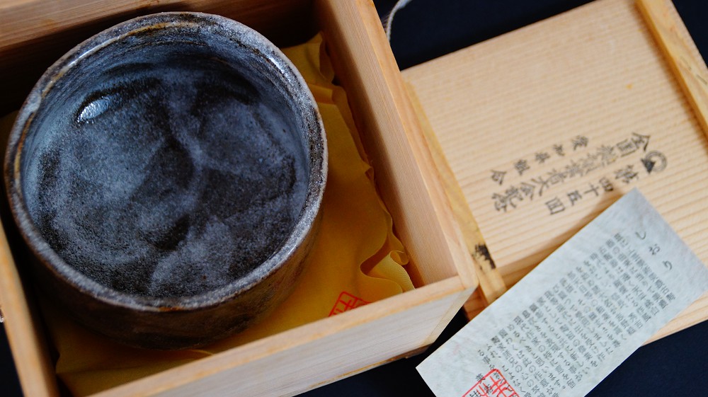 Chawan made of Shino ware by Kazufumi Wada in the opened storage box next to the certificate of authenticity