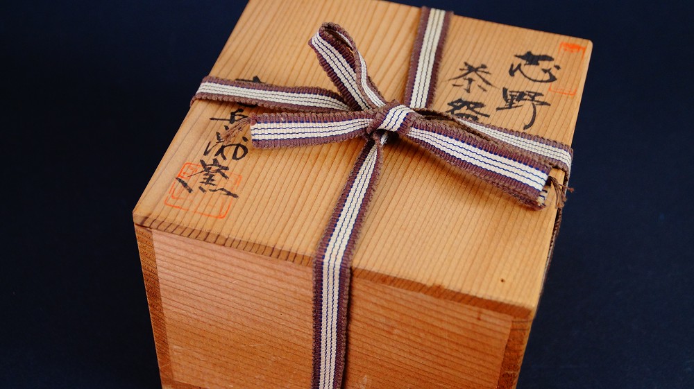 Closed storage box of the chawan made of Shino ware by Jyuzo Sato with ink inscription Shino Chawan and red artist's seal, tied with a striped cord
