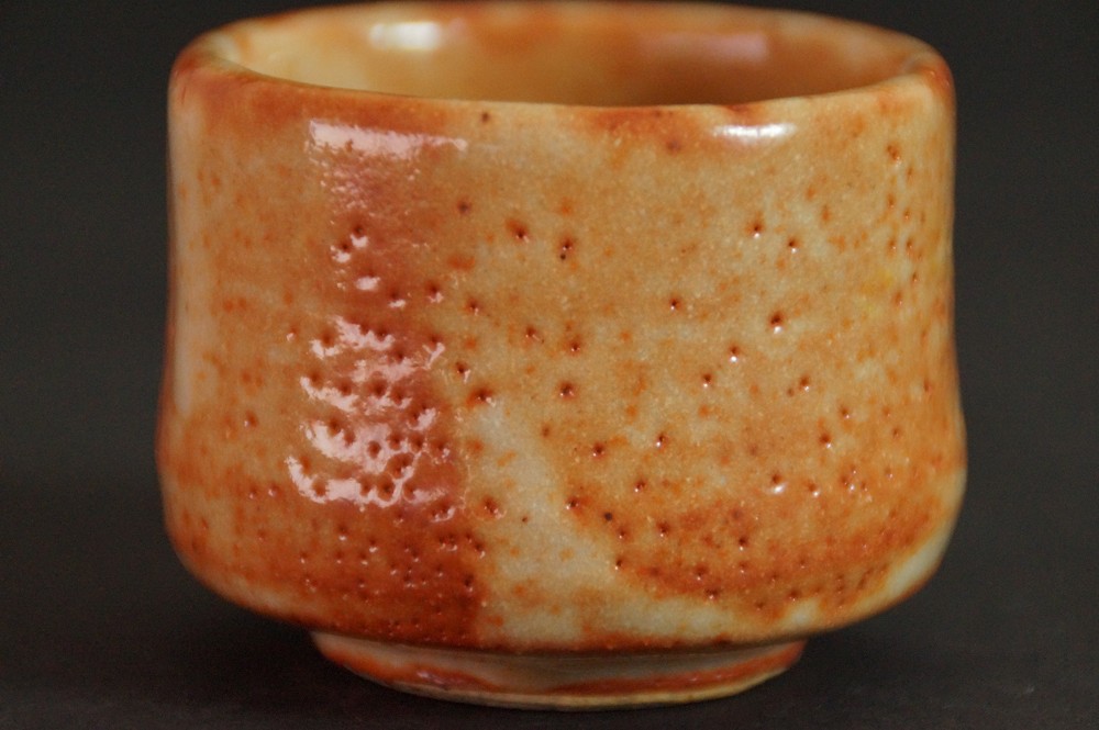 Side view of the guinomi with warm orange Shino glaze without blossom motif