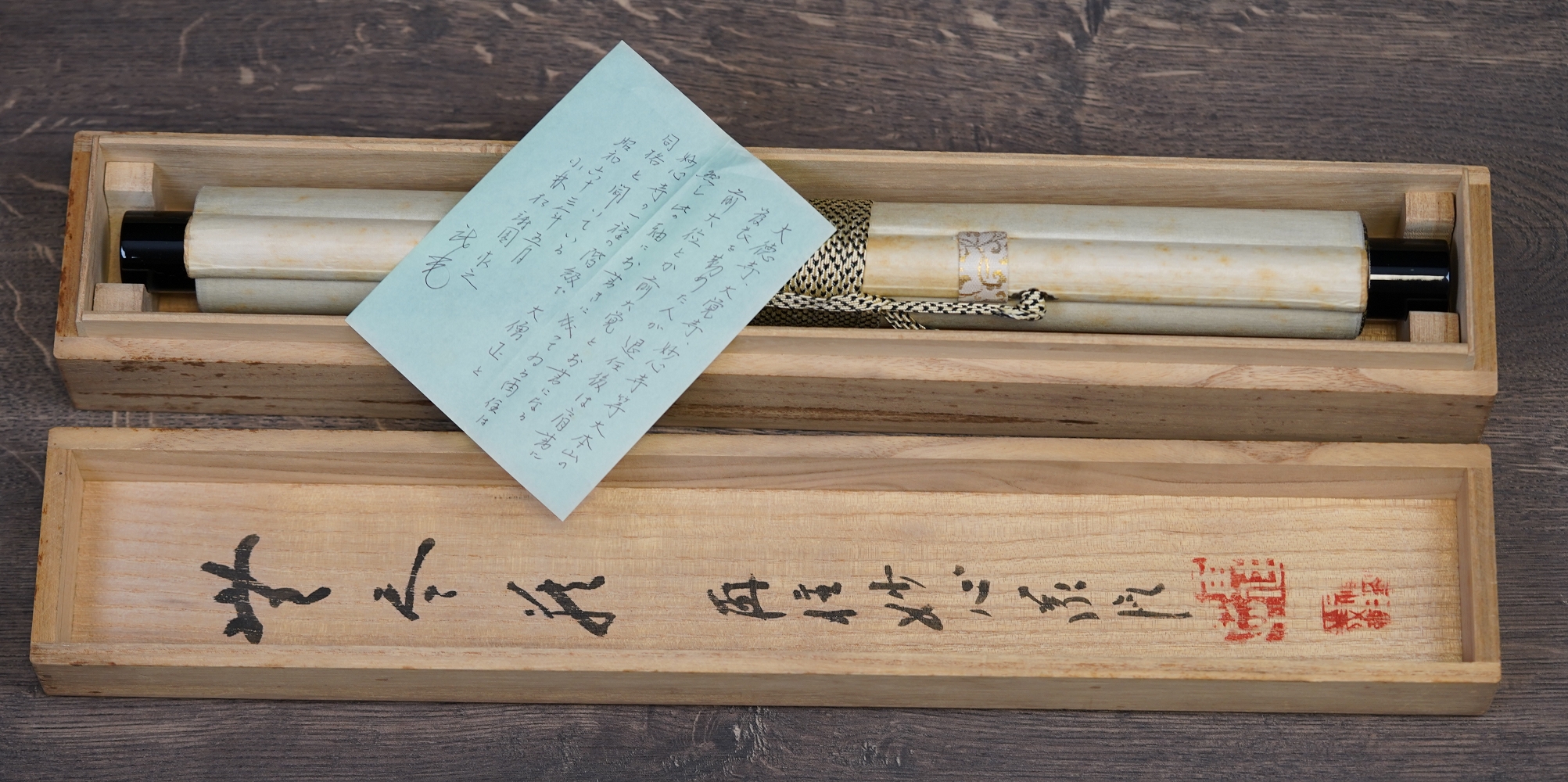 Opened storage box with rolled-up hanging scroll and handwritten accompanying note