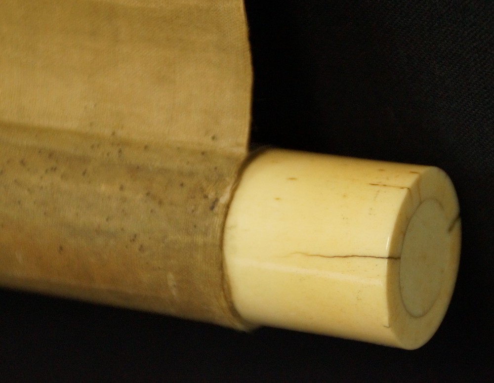 Close-up of the brightly lacquered bone jikusaki at the end of the scroll