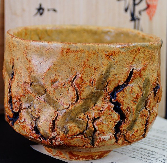Chawan made of Seto ware by Takamichi Kato with ocher-colored, deeply crackled glaze in front of the storage box