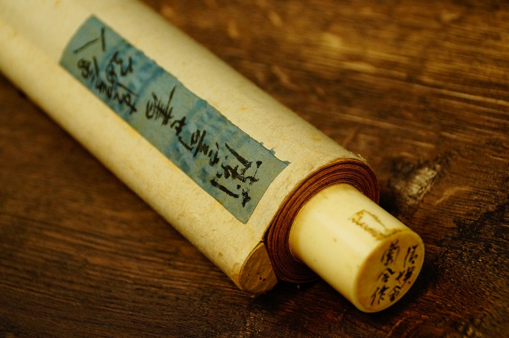Rolled up kakemono with inscribed fabric wrapper and jikusaki made of bone