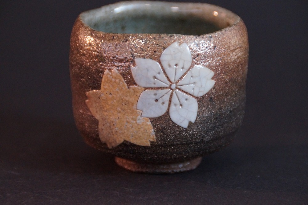 Frontalansicht der handgetoepferten Karatsu Sake Schale mit Kirschbluetenmotiv