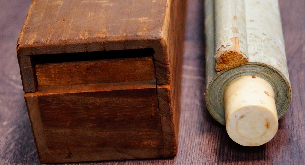 Hanging scroll by Nishioka Sosen with ivory roller ends, partially pulled out of the wooden storage box