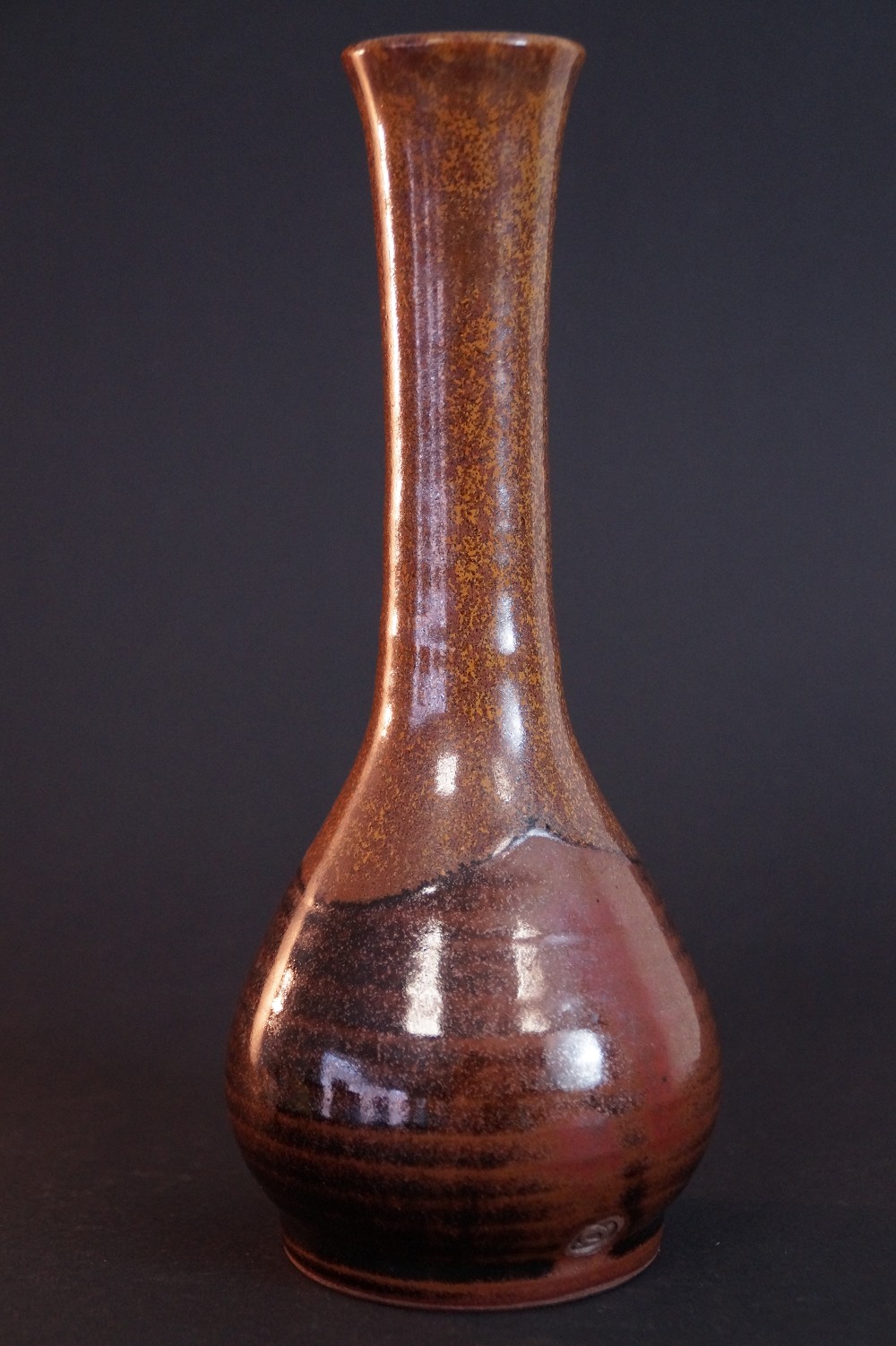 Close-up of the reddish-brown iridescent glaze with dark ash-deposit shading