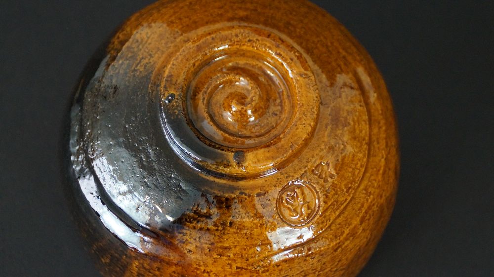 Detailansicht des spiralfoermig gedrehten Standfusses mit eingepraegtem Kuenstlersiegel der Chawan Teeschale aus Ohi-Keramik