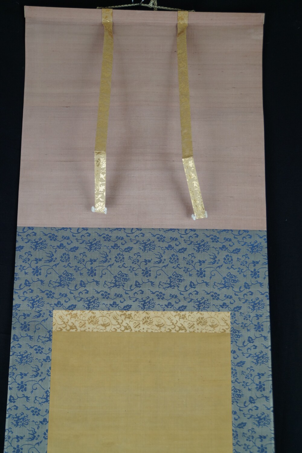 Detailansicht der rosafarbenen Seide und blau gebluemten Brokatmontierung der Rueckzug-Rolle im Kakemono-Set von Kano Eihaku