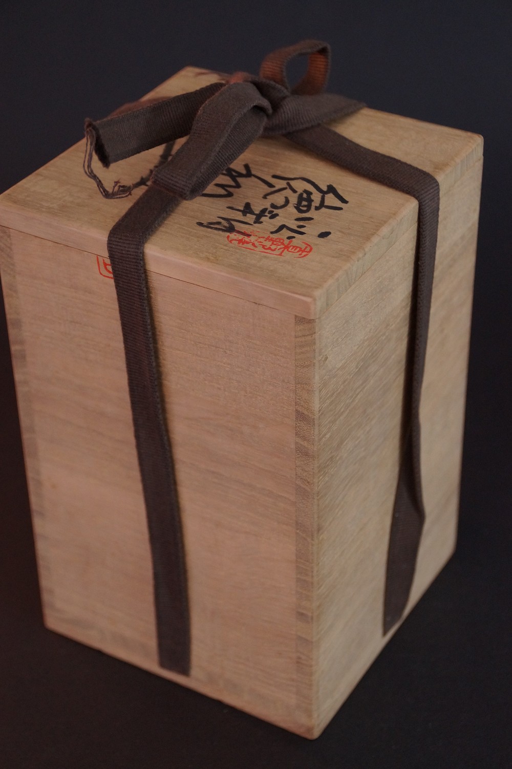 The closed storage box with brown cord and handwritten signature of the master potter