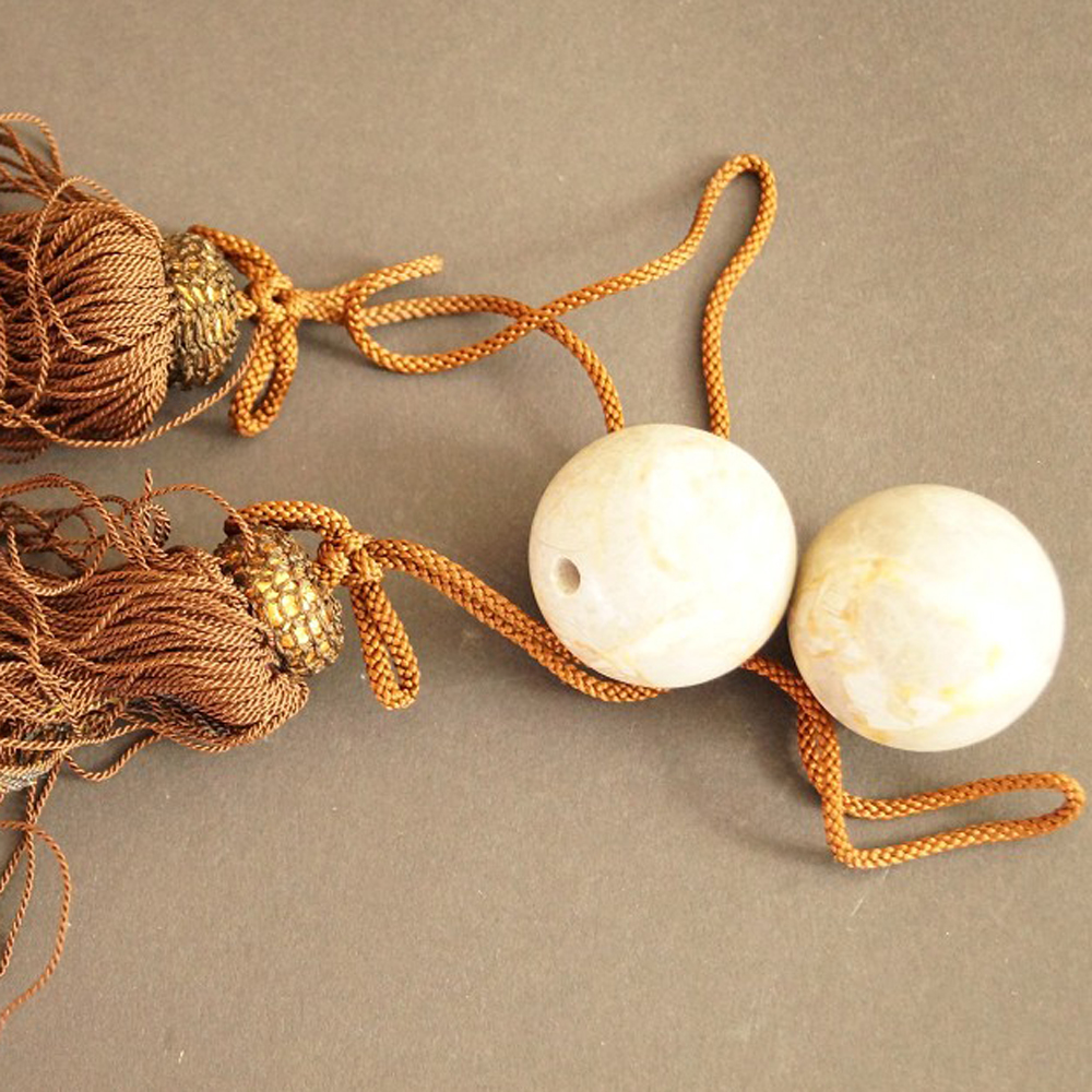 Two beige marbled natural stone balls with brown silk tassels set close-up preview