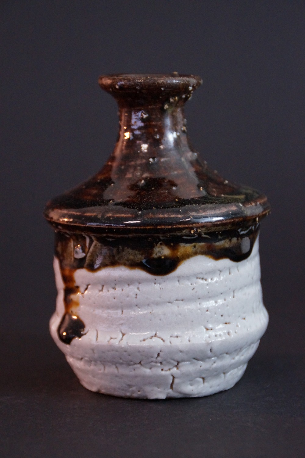 Side view of the tokkuri with flowing glaze traces over white clay body