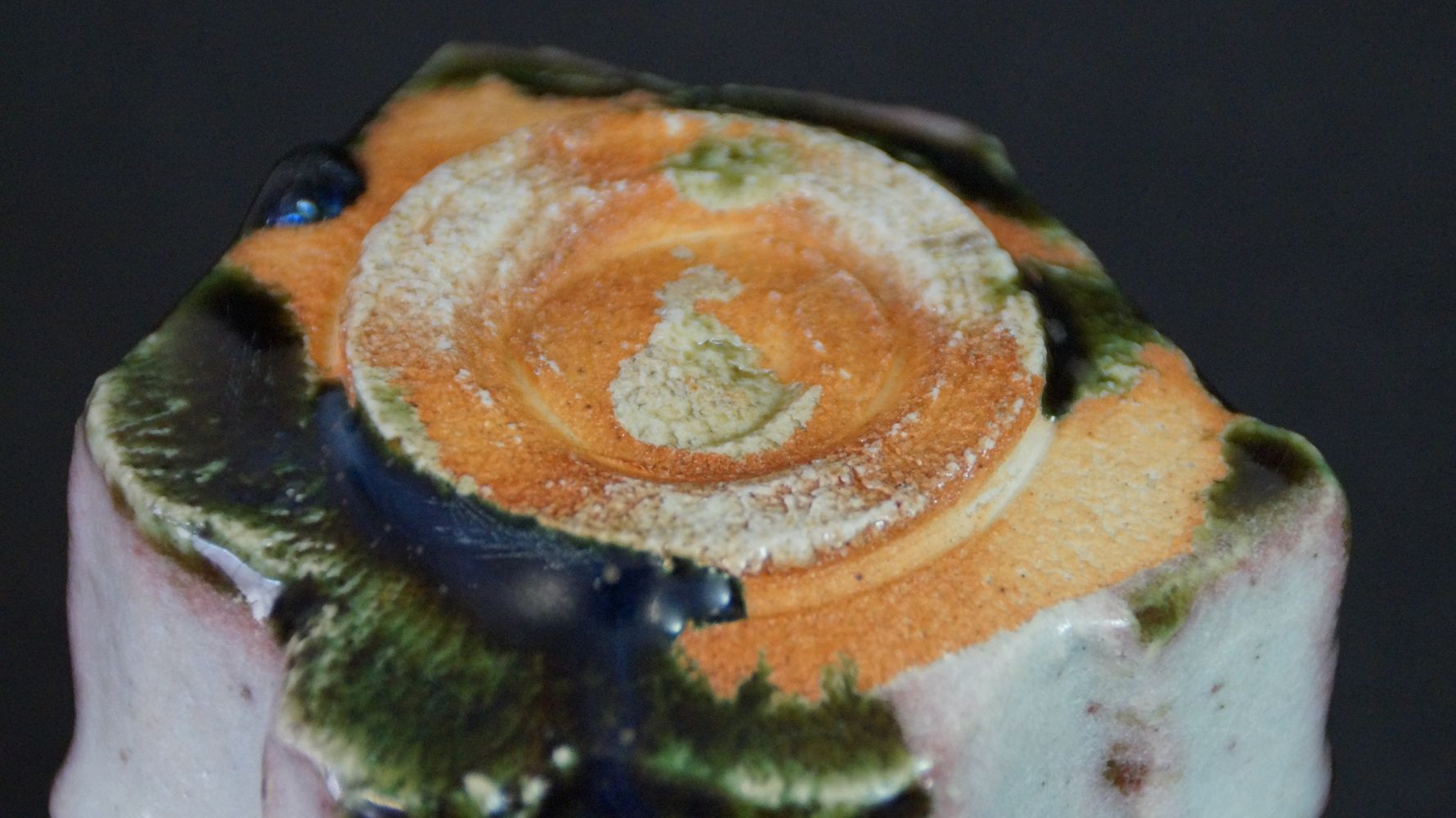 Detail view of the unglazed, orange-colored foot of the guinomi sake cup made of Oribe ware
