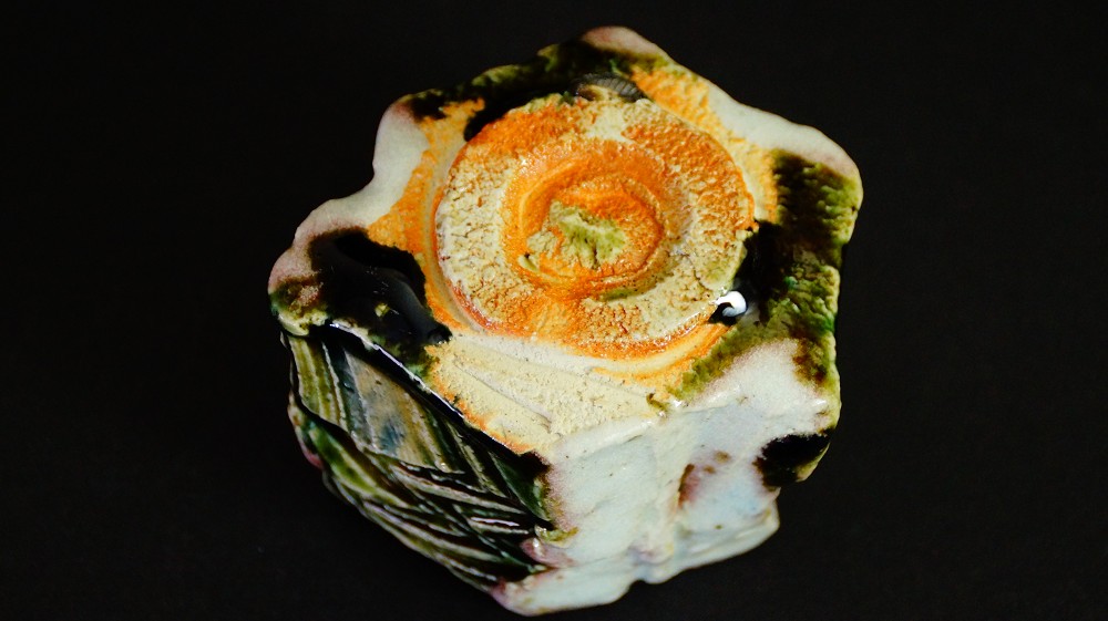 Close-up of the unglazed base with spiral-shaped orange fire mark of the guinomi