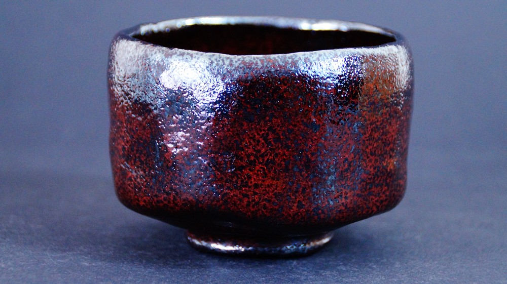 Chawan made of Raku ware by Shoraku Sasaki in front view with a mottled reddish-brown and black glaze