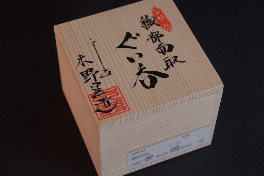 Close-up of the box lid with the inscription Oribe Mentori Guinomi and red artist seal