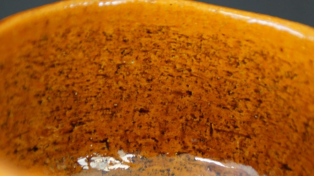 Extreme close-up of the speckled orange glaze texture of the Chawan tea bowl made of Ohi ware