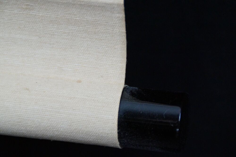 Detailansicht des schwarz lackierten Rollenendes mit cremefarbener Seide des Kakemono Welpe im Abendrot unter Kiefern
