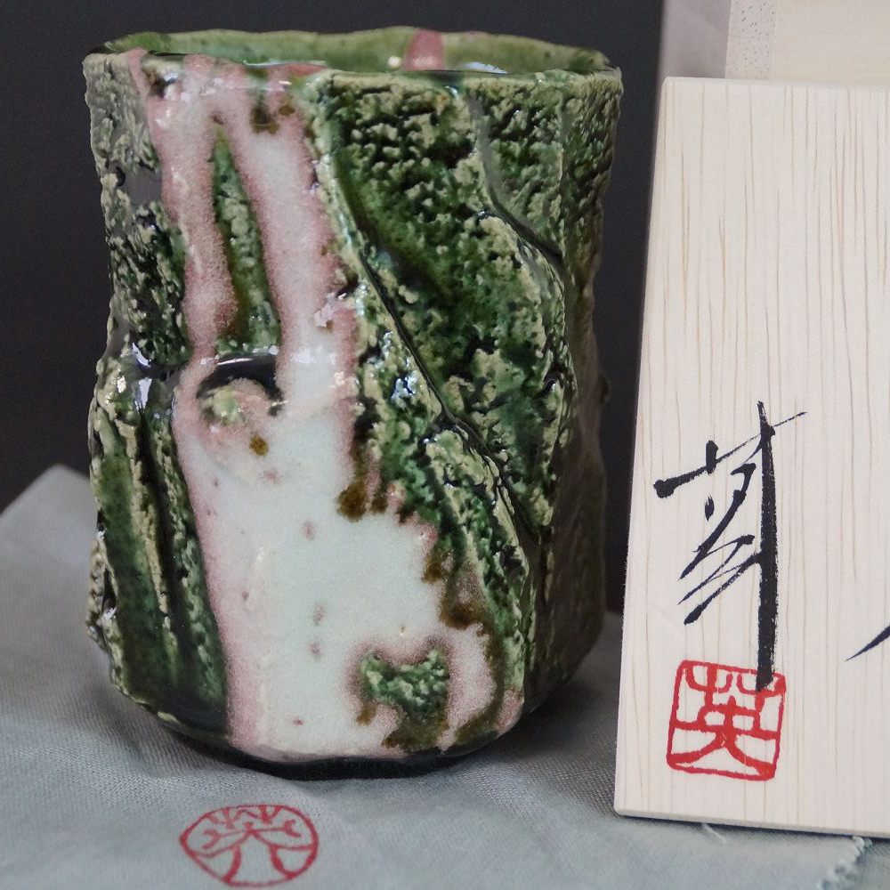 Yunomi tea bowl made of Oribe ware by Kawachi Hidetoshi in full view with green-pink-white patterned glaze