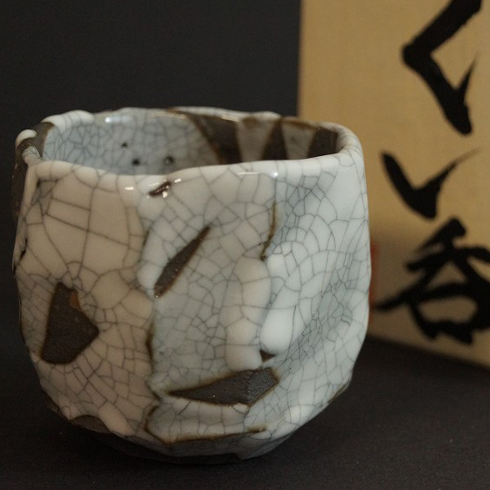 Shino ware sake cup with crackled glaze next to labeled storage box Motif Close-Up Preview