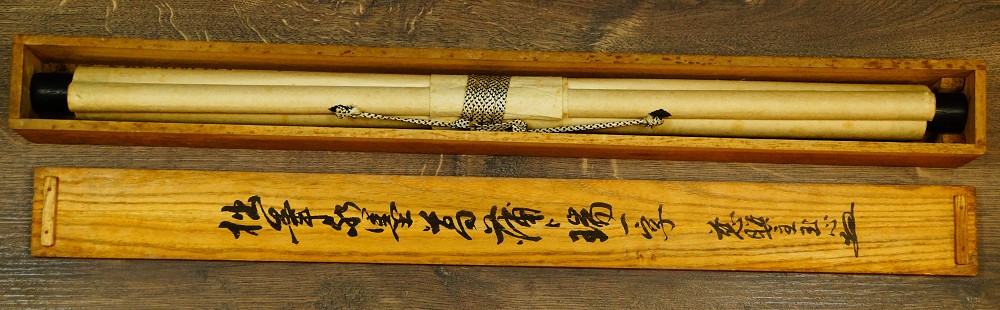 Rolled hanging scroll in the opened wooden box next to the inscribed lid
