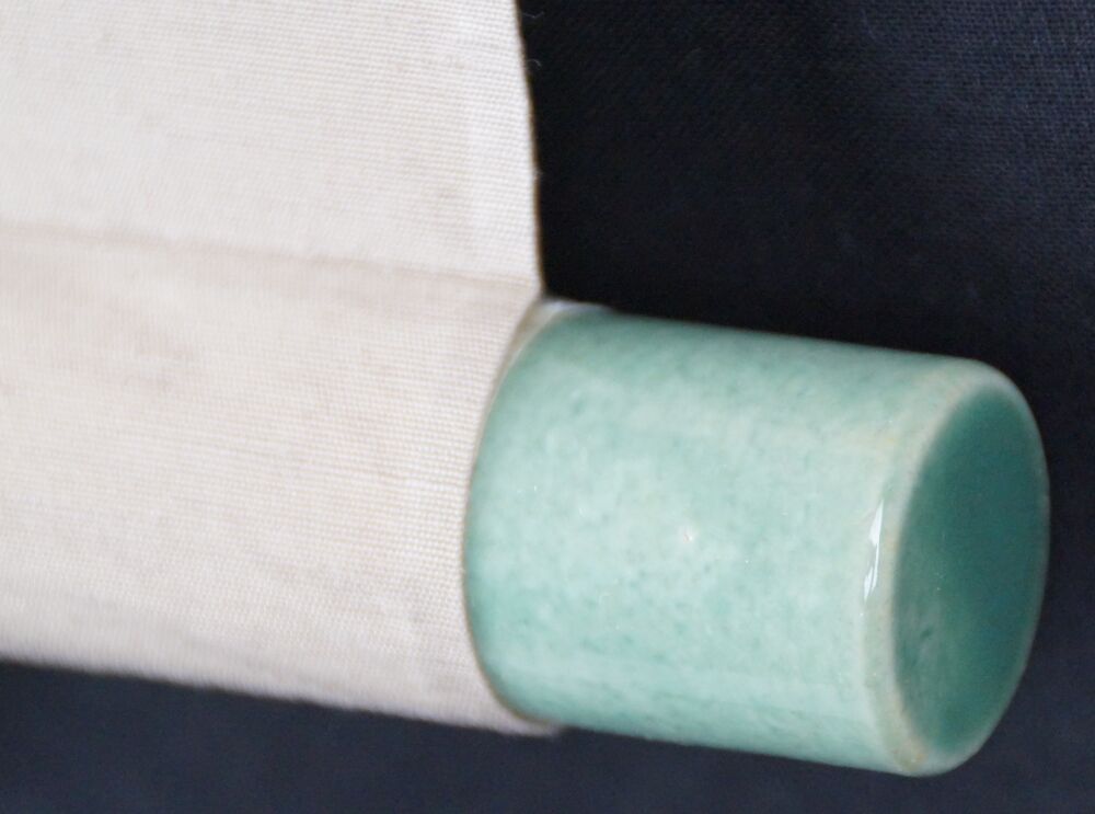 Detail view of the scroll end with green jade knob and cream-colored silk of the kakemono songbird on blossoming plum tree
