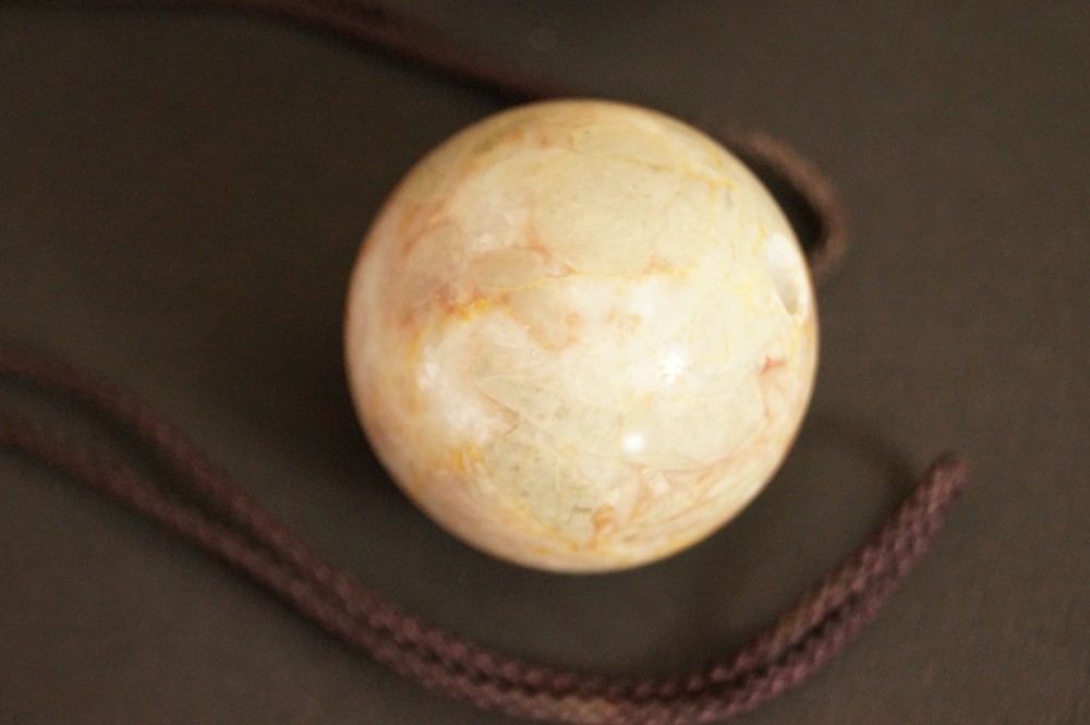 Greenish beige veined stone sphere with cord Stone Close-Up 3