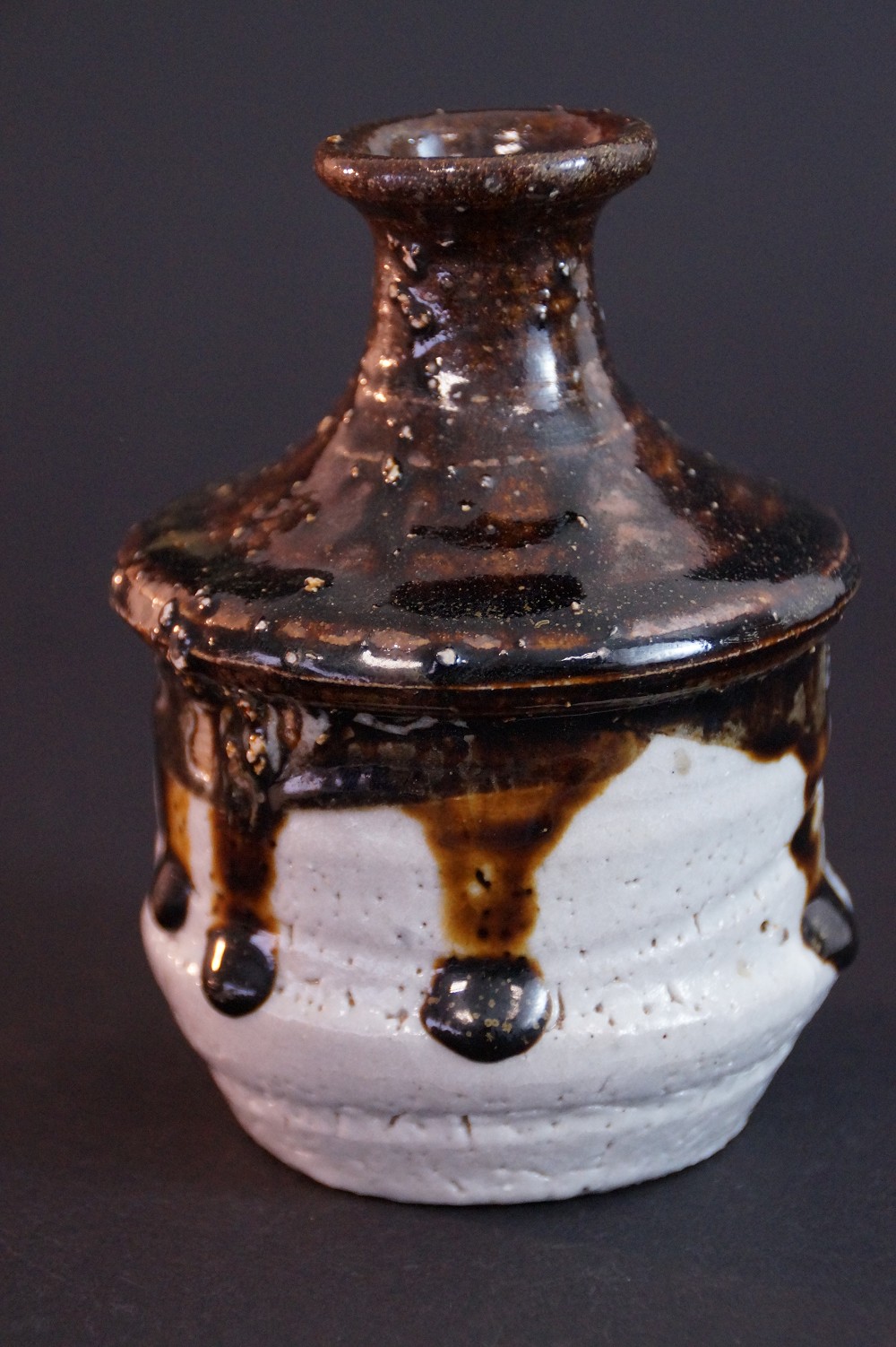 Close-up of the drop-shaped, dripping dark glaze on white clay body